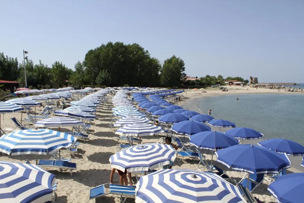 Spiaggia attrezzata con file di ombrelloni a righe blu e bianche vicino al mare