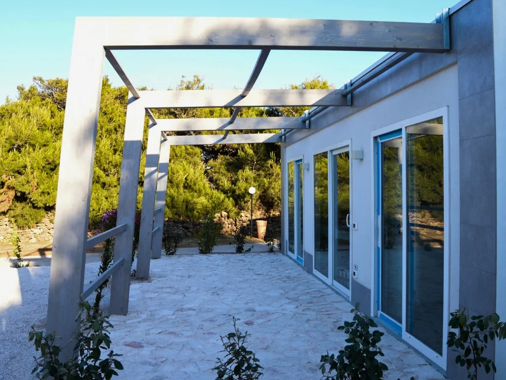 Terrazza esterna con pergolato in legno e ampie vetrate immersa nel verde