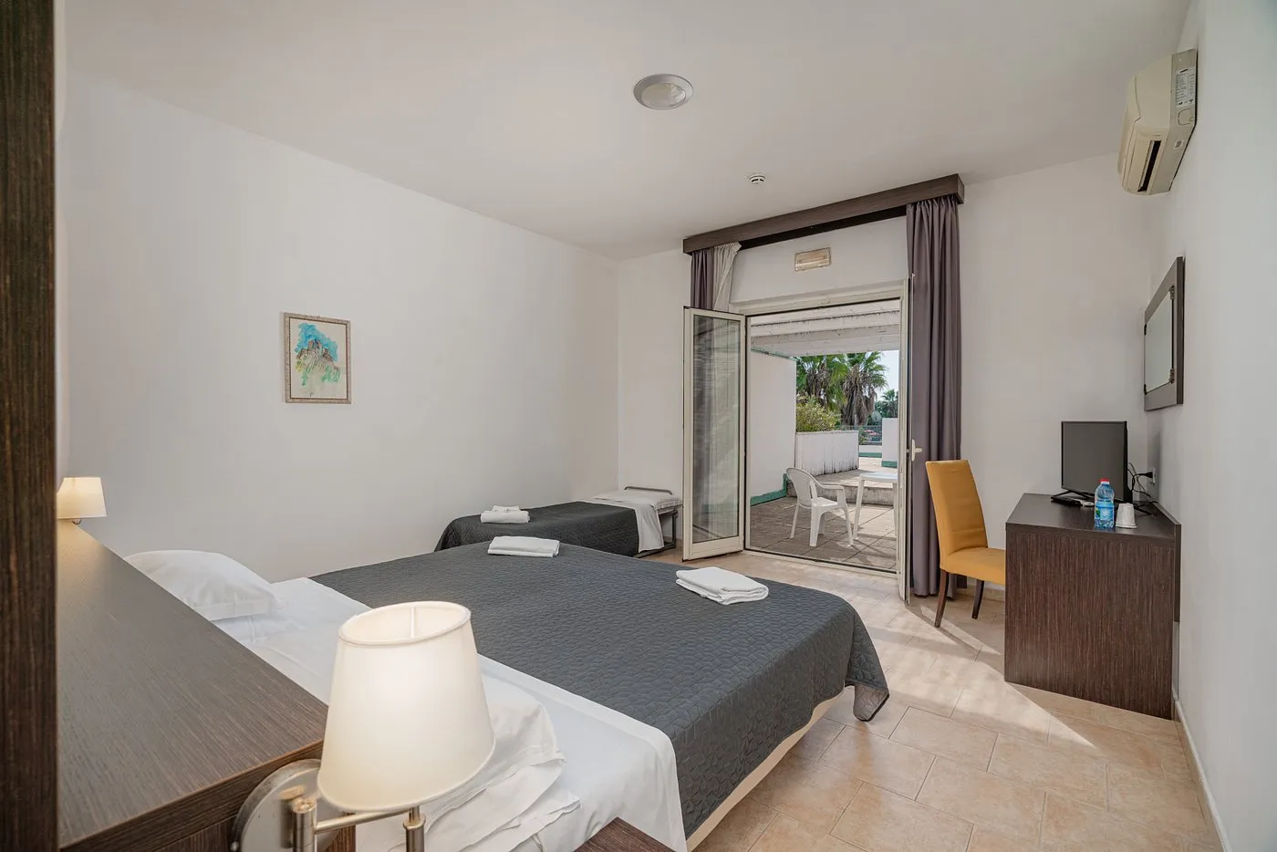 Camera con letto matrimoniale e singolo e accesso a patio esterno
