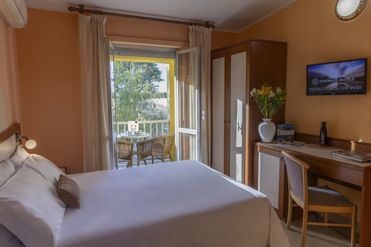 Camera con letto matrimoniale, scrivania, TV e accesso al balcone