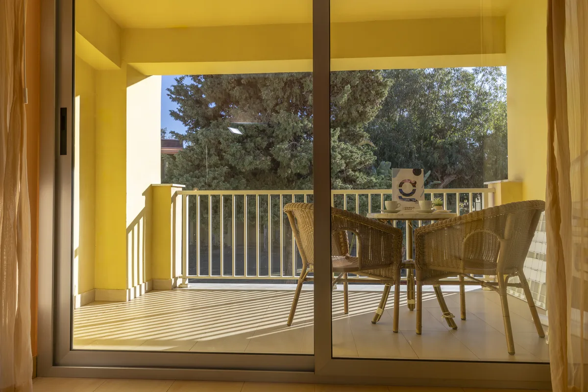 Vista del balcone con tavolino e poltrone in vimini affacciato sul verde