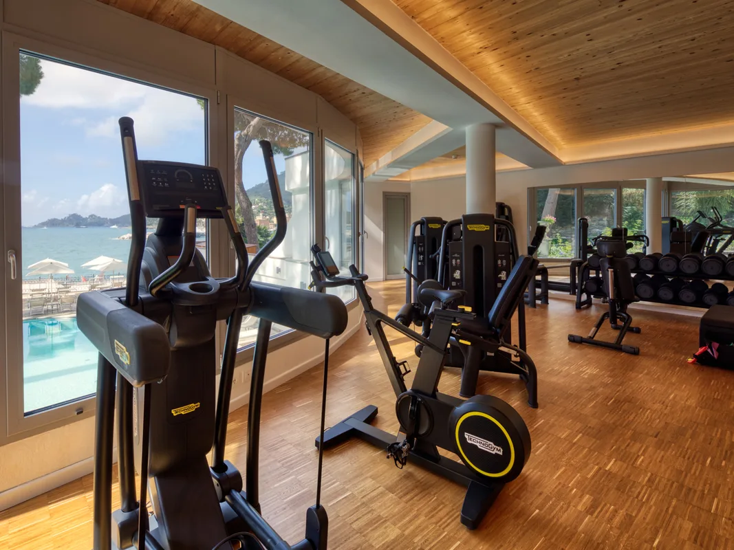 Palestra attrezzata con macchinari Technogym e ampie vetrate con vista sulla piscina e il mare