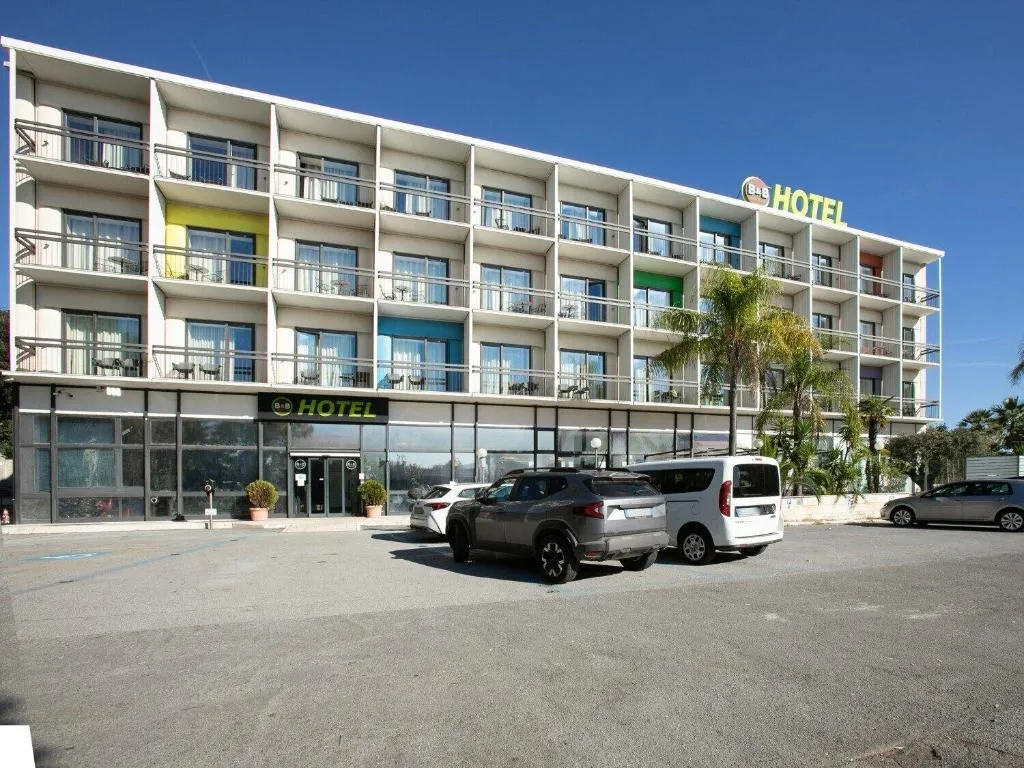 Facciata esterna dell'hotel B&B con balconi colorati, parcheggio e palme