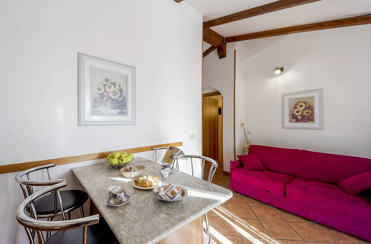 Soggiorno luminoso con divano fucsia, tavolo da pranzo e quadri di girasoli