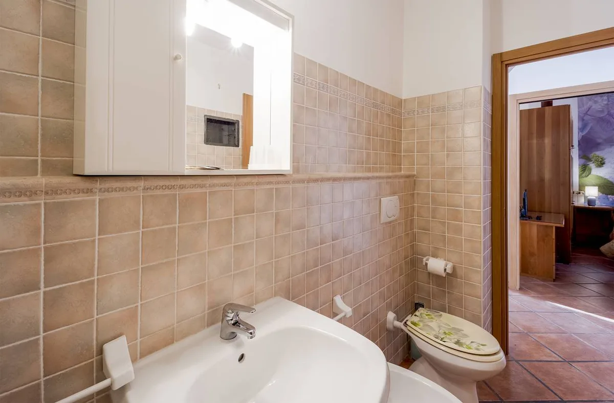 Bagno con lavabo, specchio e piastrelle beige in tonalità calde