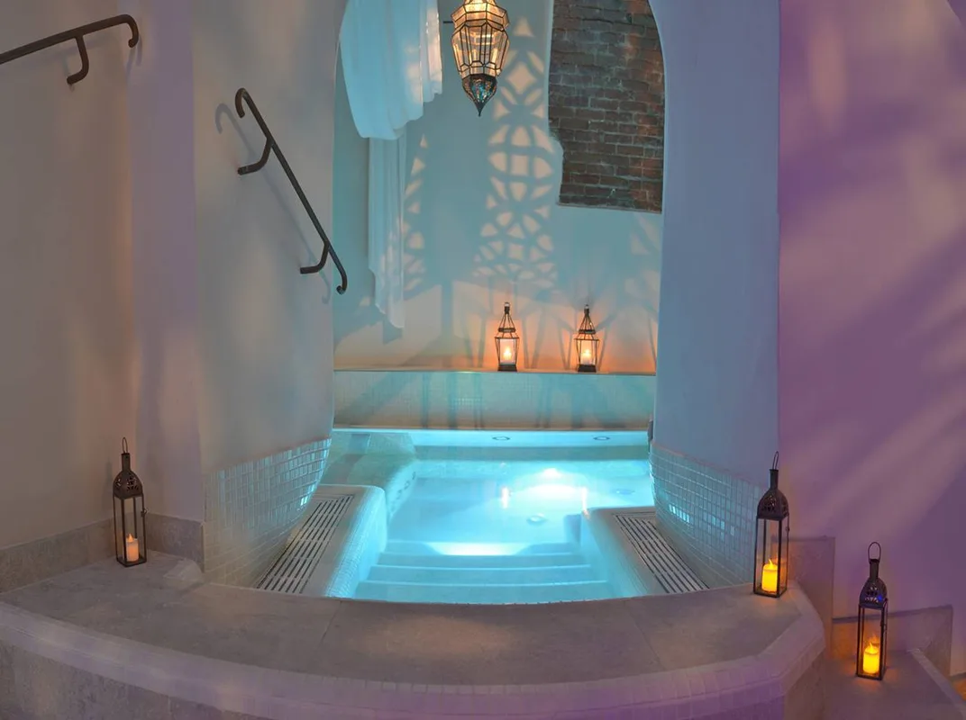 Vasca idromassaggio della spa con illuminazione azzurra e lanterne a candela