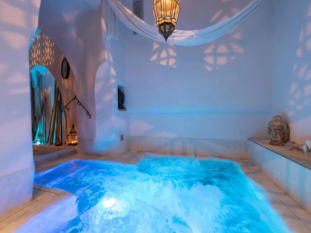 Vasca idromassaggio della spa con luci blu, lanterna marocchina e decorazioni orientali