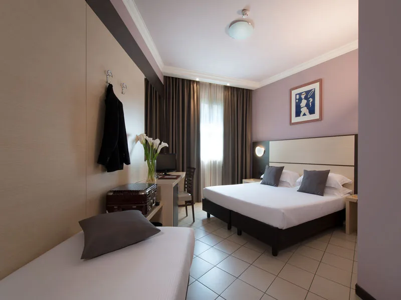 Camera con letto matrimoniale, scrivania e appendiabiti con valigia vintage