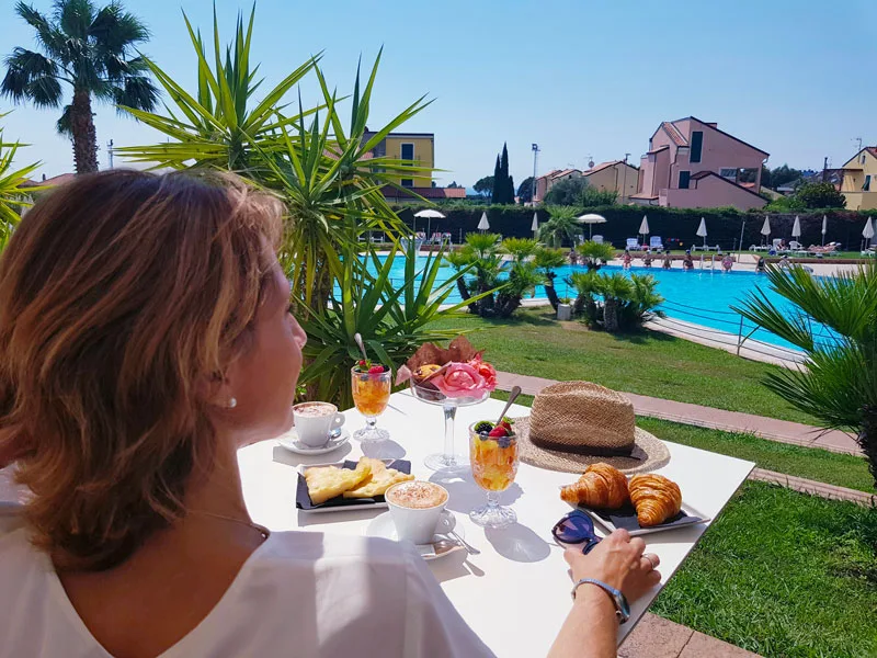 Colazione all'aperto con cappuccino, cornetti e macedonia vista piscina