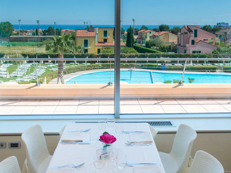 Tavolo apparecchiato del ristorante con vista sulla piscina e sul mare
