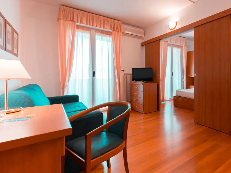 Soggiorno della camera con divano, scrivania, TV e camera da letto