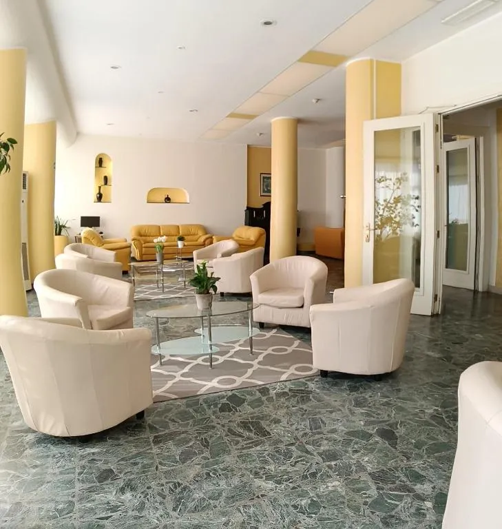 Hall dell'hotel con poltrone bianche e pavimento in marmo verde