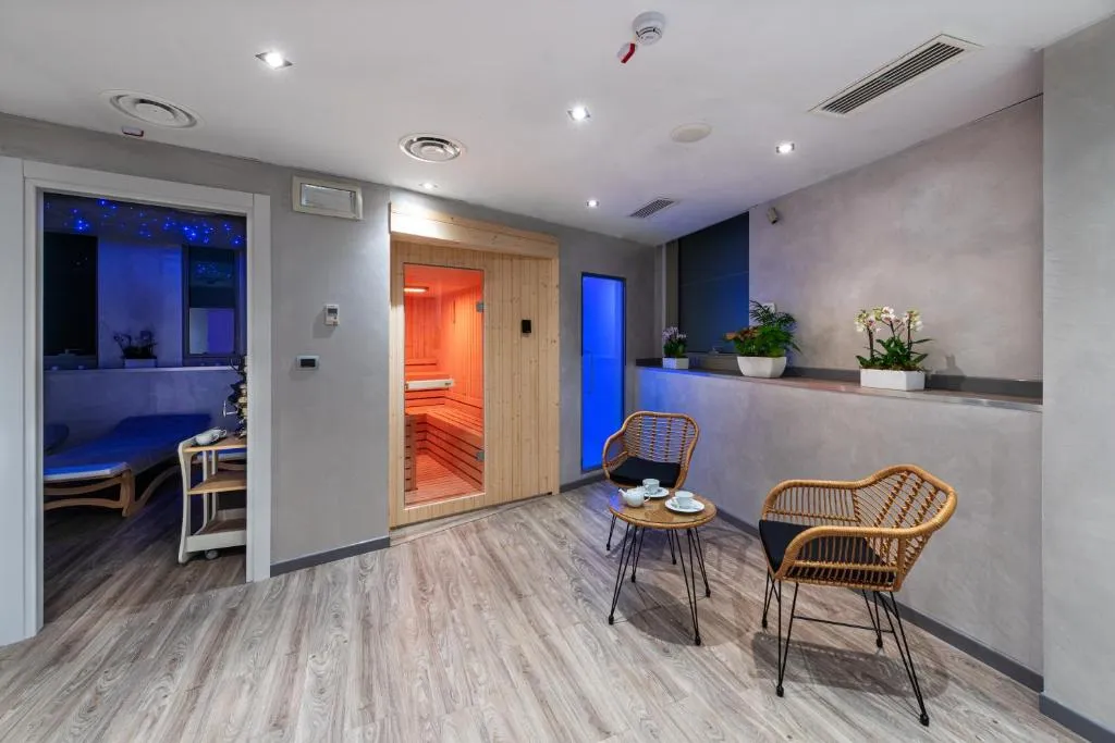 Area benessere con sauna in legno, zona relax con poltrone in rattan e illuminazione soffusa
