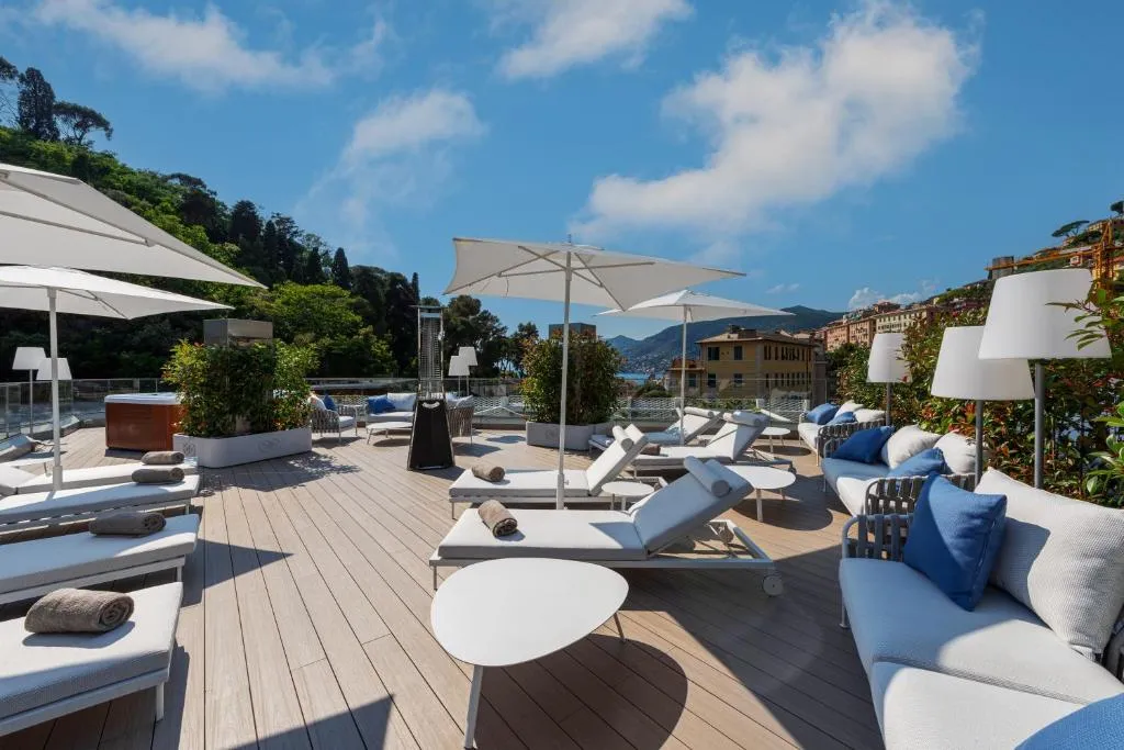 Terrazza solarium con lettini, ombrelloni bianchi e divani con vista sulle colline