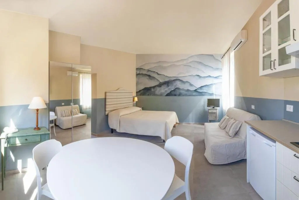 Monolocale con letto, divano, angolo cottura e murale di montagne