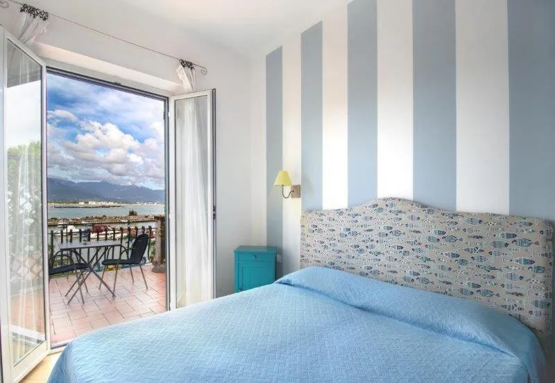 Camera con pareti a righe azzurre e balcone con vista sul porto