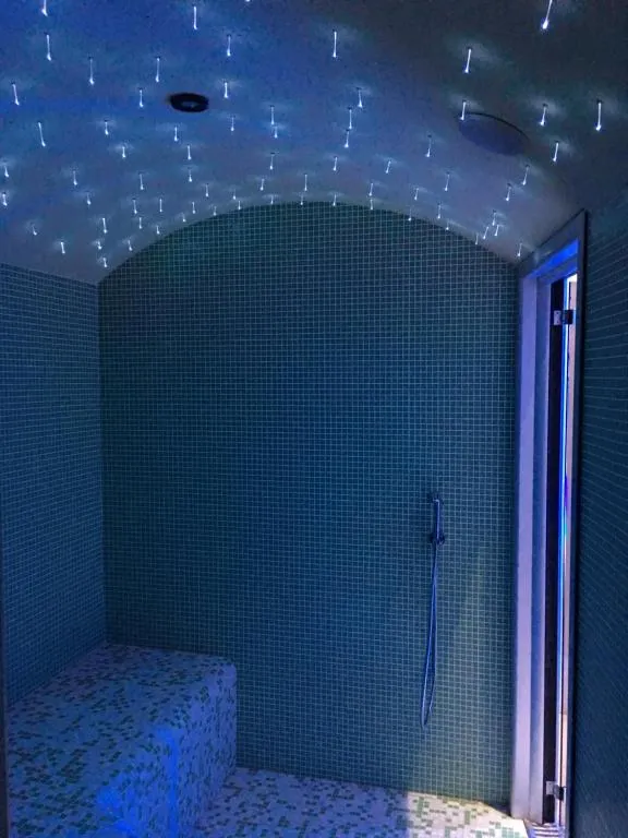 Bagno turco con mosaico azzurro, soffitto a volta illuminato con luci a stella e doccia