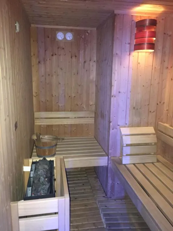 Sauna finlandese in legno con panche, stufa e secchio per l'acqua