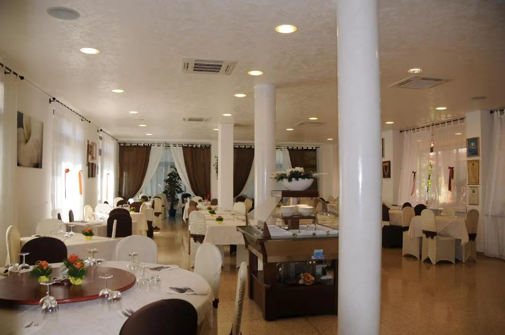 Sala ristorante luminosa con tavoli apparecchiati, colonne bianche e zona buffet