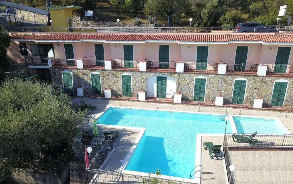 Vista dall'alto della struttura con piscine e camere con persiane verdi