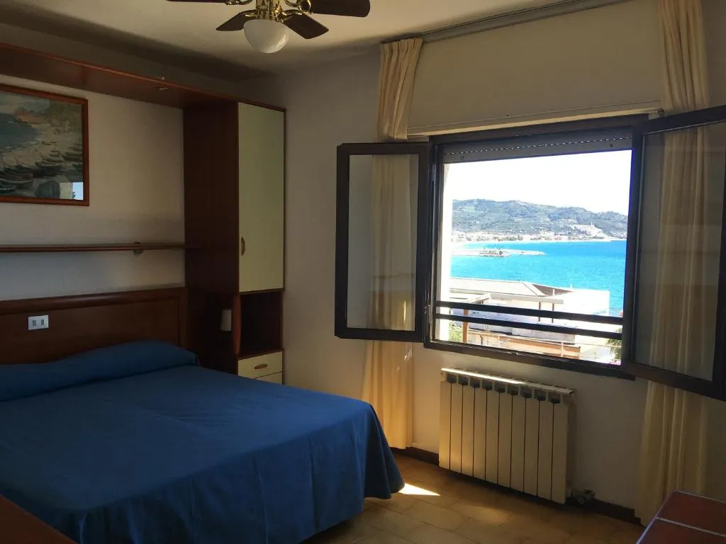 Camera con letto blu e ampia finestra panoramica sul mare