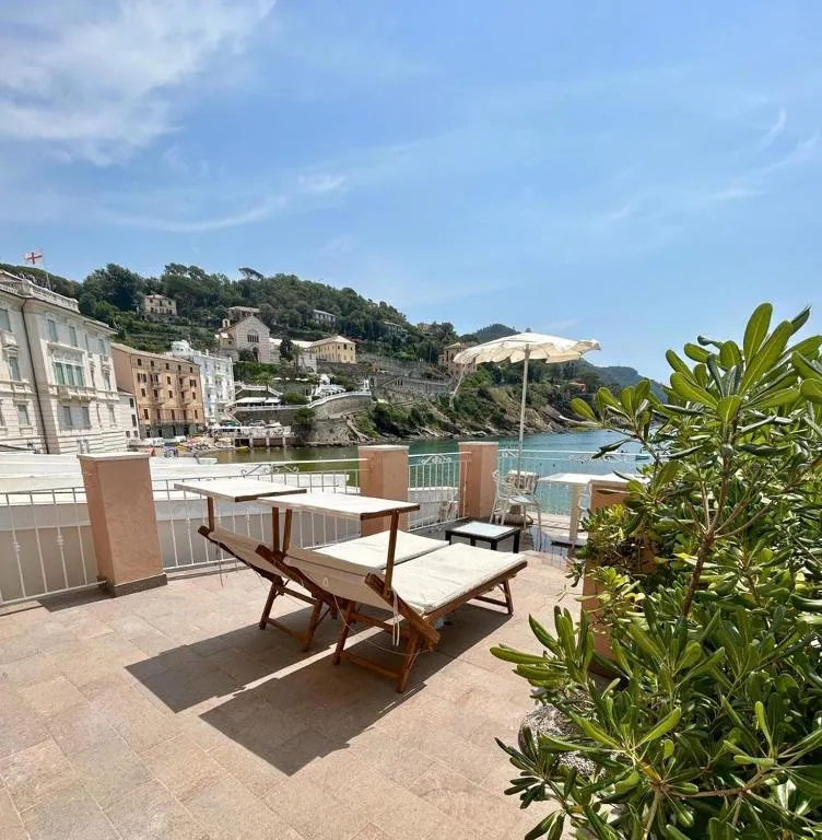 Terrazza panoramica con lettini prendisole e ombrellone affacciata sulla baia e sulla costa