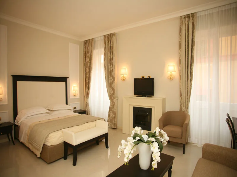 Spaziosa camera con letto matrimoniale, camino, poltrone e tende eleganti