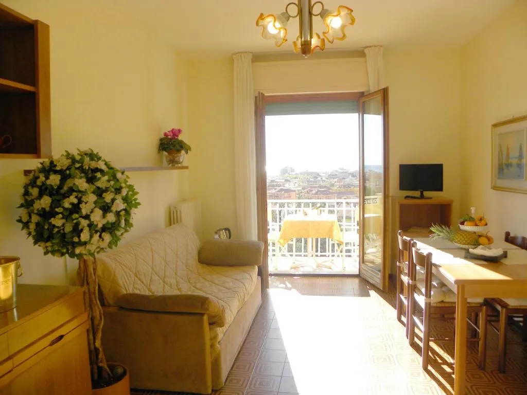 Soggiorno luminoso con divano, tavolo da pranzo e balcone con vista sulla città e sul mare