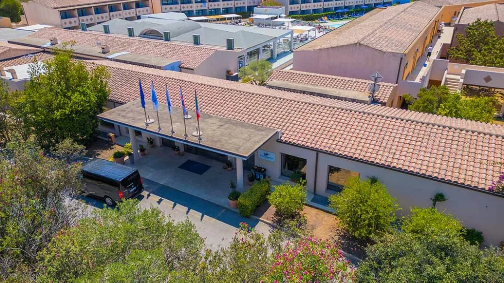 Ingresso del resort con pensilina, bandiere e vegetazione mediterranea