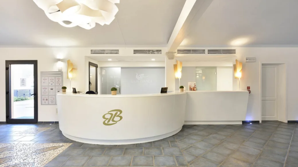 Reception del resort con bancone bianco curvo e illuminazione moderna
