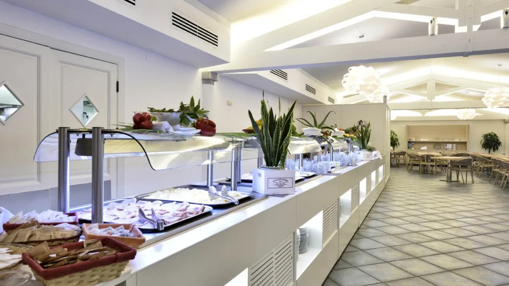 Buffet del ristorante con piatti caldi e sala da pranzo sullo sfondo