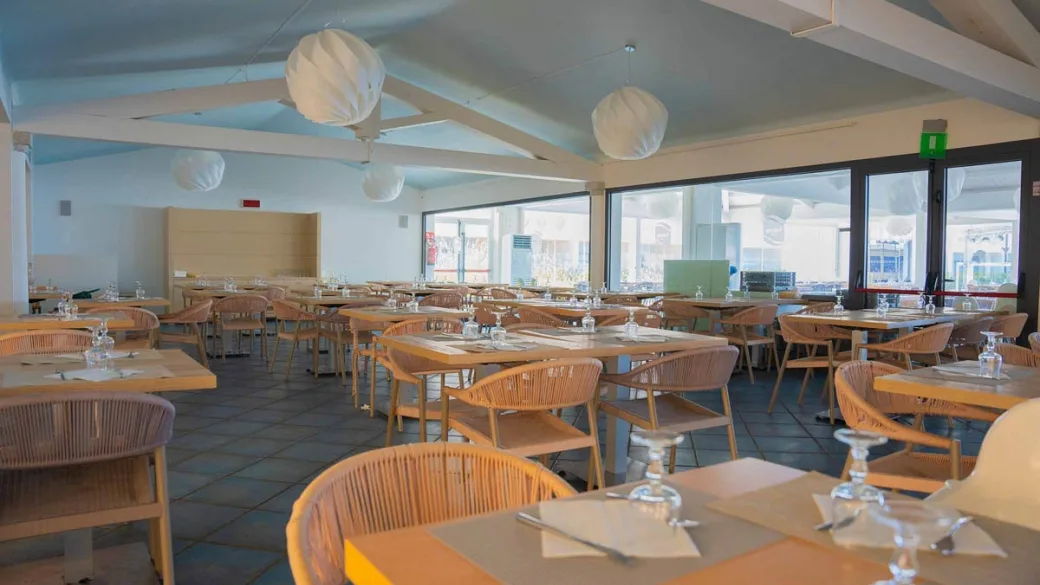 Sala ristorante con tavoli apparecchiati e tetto in legno bianco