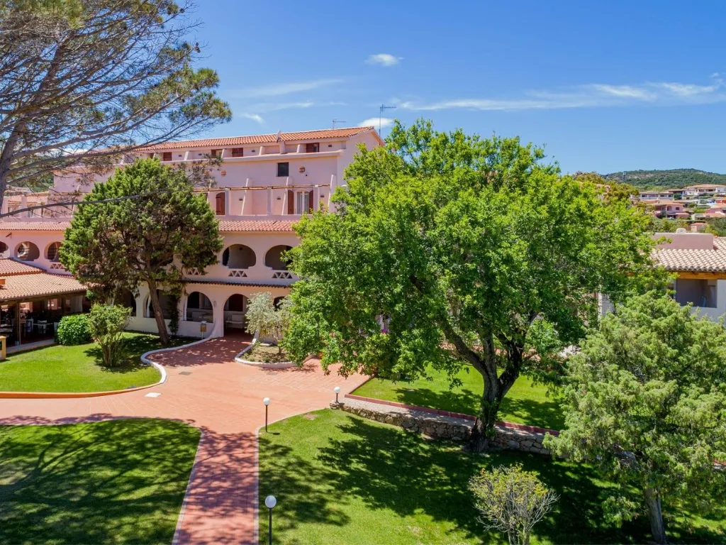 Esterno dell'hotel in stile mediterraneo con giardino curato e grande albero