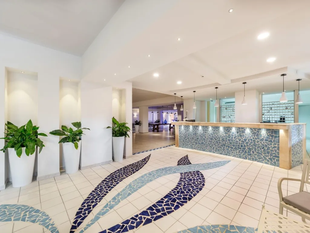 Reception dell'hotel con pavimento decorato a mosaico blu e piante ornamentali