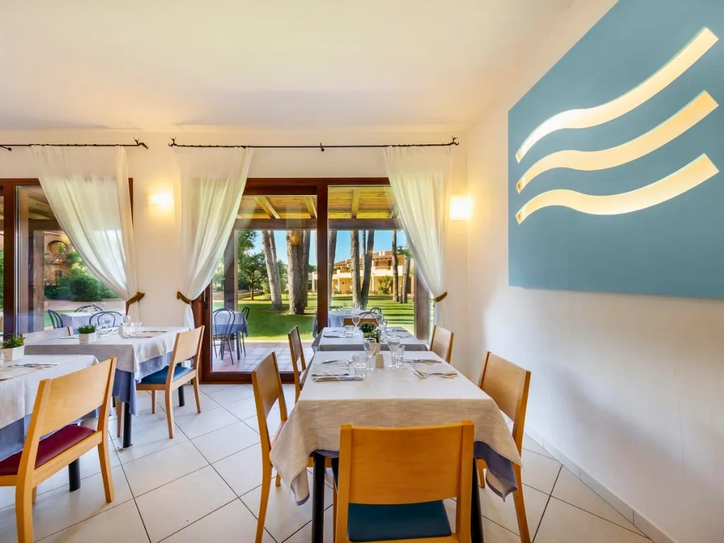 Sala ristorante con tavoli apparecchiati e vista sul giardino attraverso le vetrate
