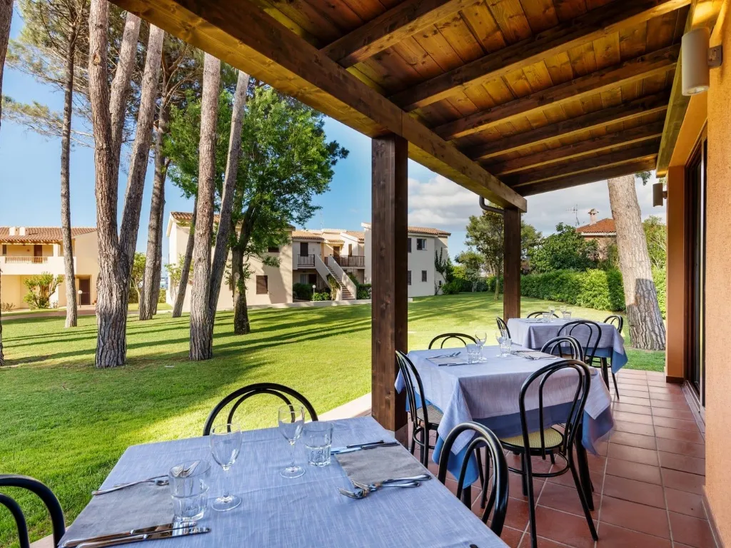 Terrazza ristorante coperta con tavoli apparecchiati e vista sul giardino