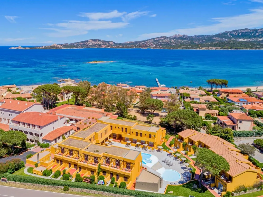 Veduta aerea del resort giallo con piscina e baia turchese panoramica