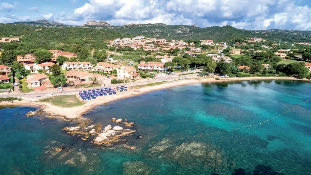 Veduta aerea della costa con spiaggia, ombrelloni blu e acque cristalline