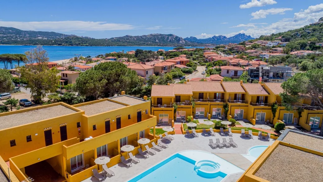 Vista dall'alto del resort con piscina, ombrelloni e mare in lontananza