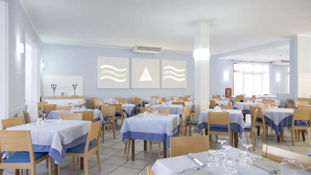 Sala da pranzo luminosa con tavoli apparecchiati e decorazioni a parete