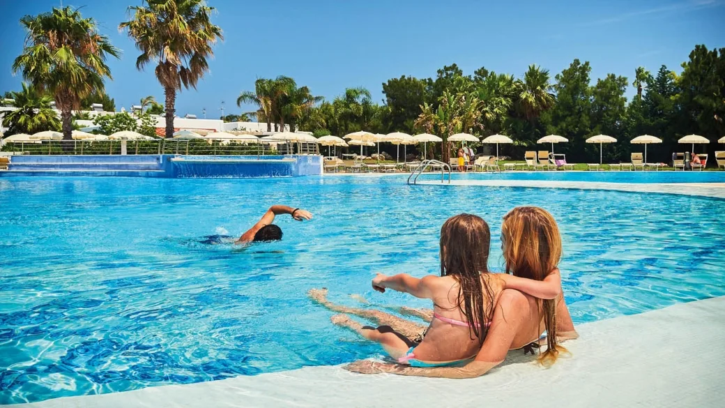 Famiglia che si rilassa e gioca nella piscina del resort circondata da palme