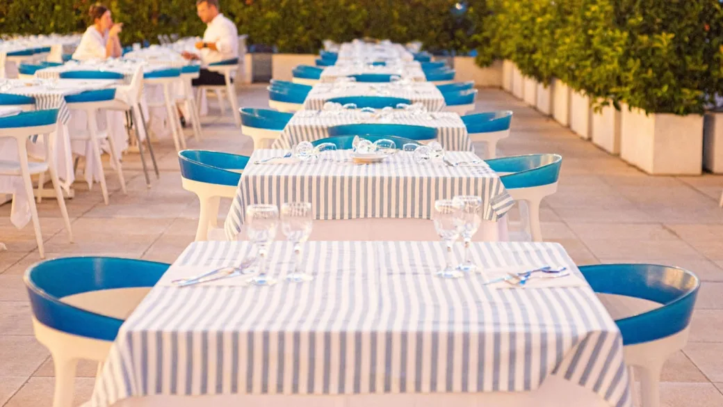 Tavoli del ristorante in terrazza con tovaglie a righe e sedie blu