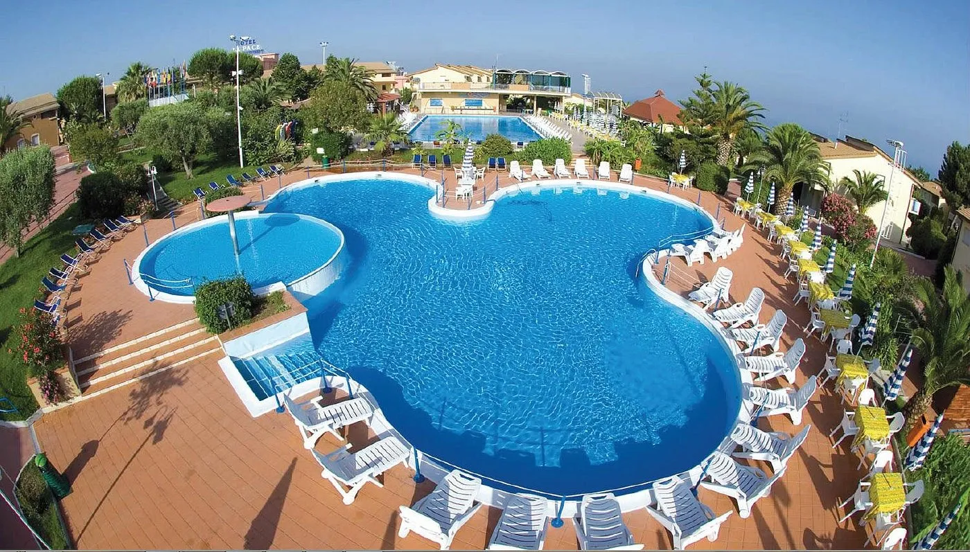 Vista aerea di piscina a forma di trifoglio con lettini bianchi e pavimentazione rossa