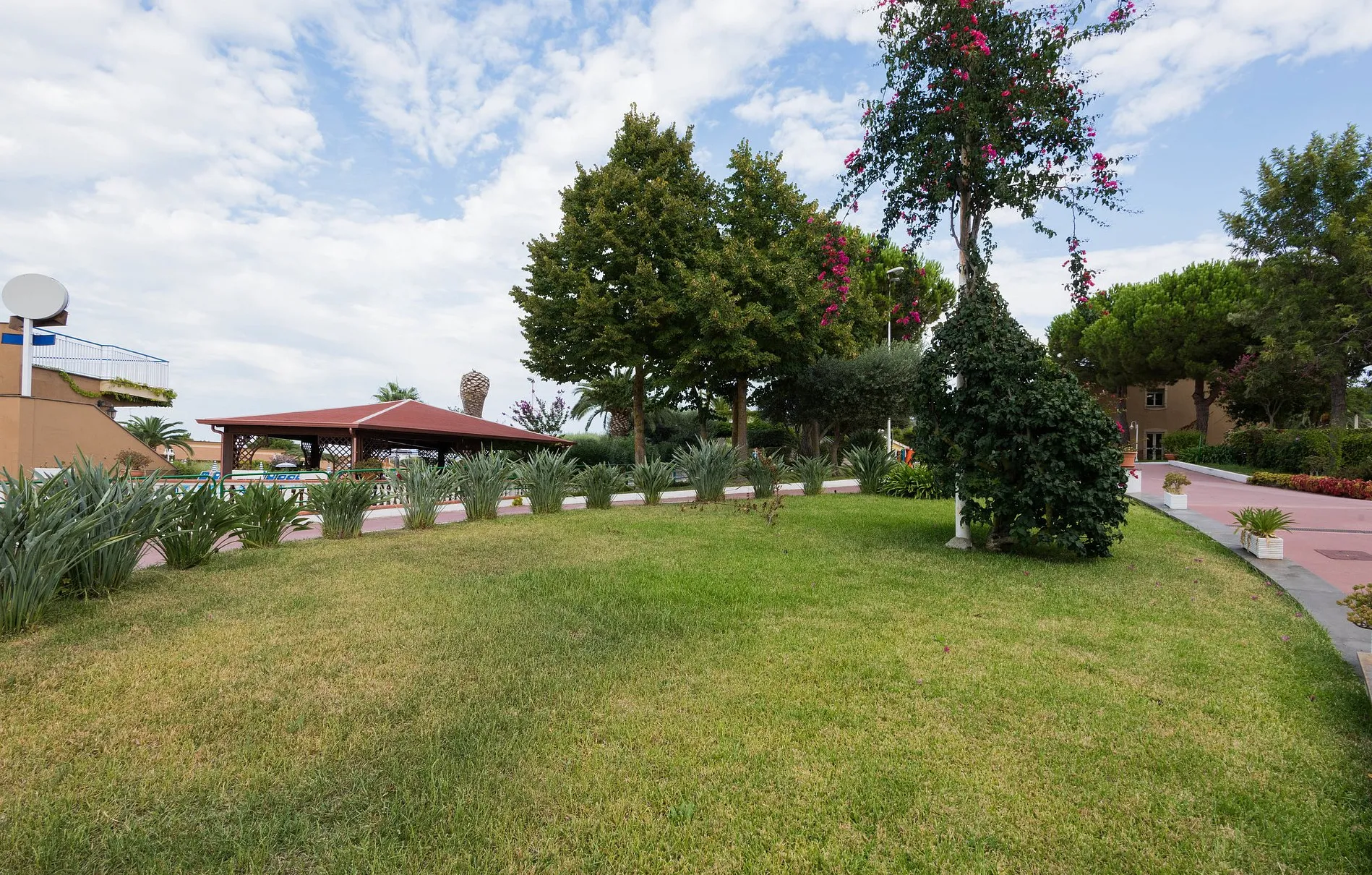 Ampio giardino verde con alberi, fiori e gazebo nel resort