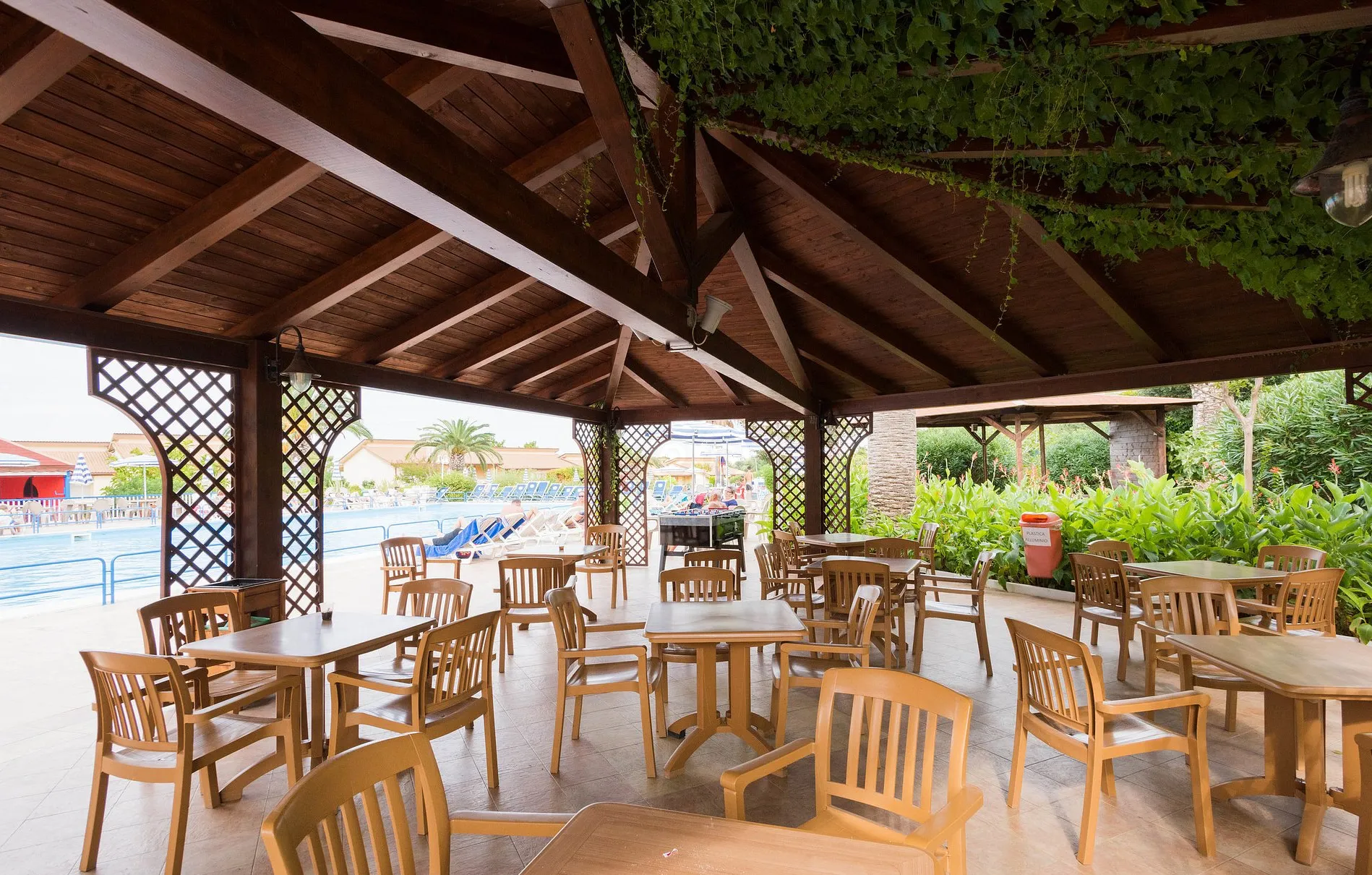 Area bar coperta da gazebo in legno con tavoli e sedie a bordo piscina