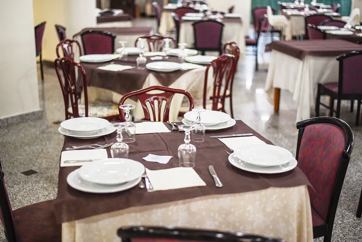 Sala ristorante interna con tavoli apparecchiati, tovaglie bordeaux e bicchieri