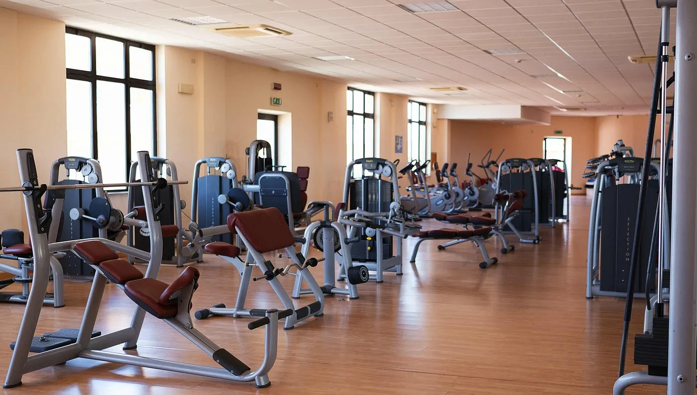 Sala fitness attrezzata con macchinari per allenamento e pavimento in parquet