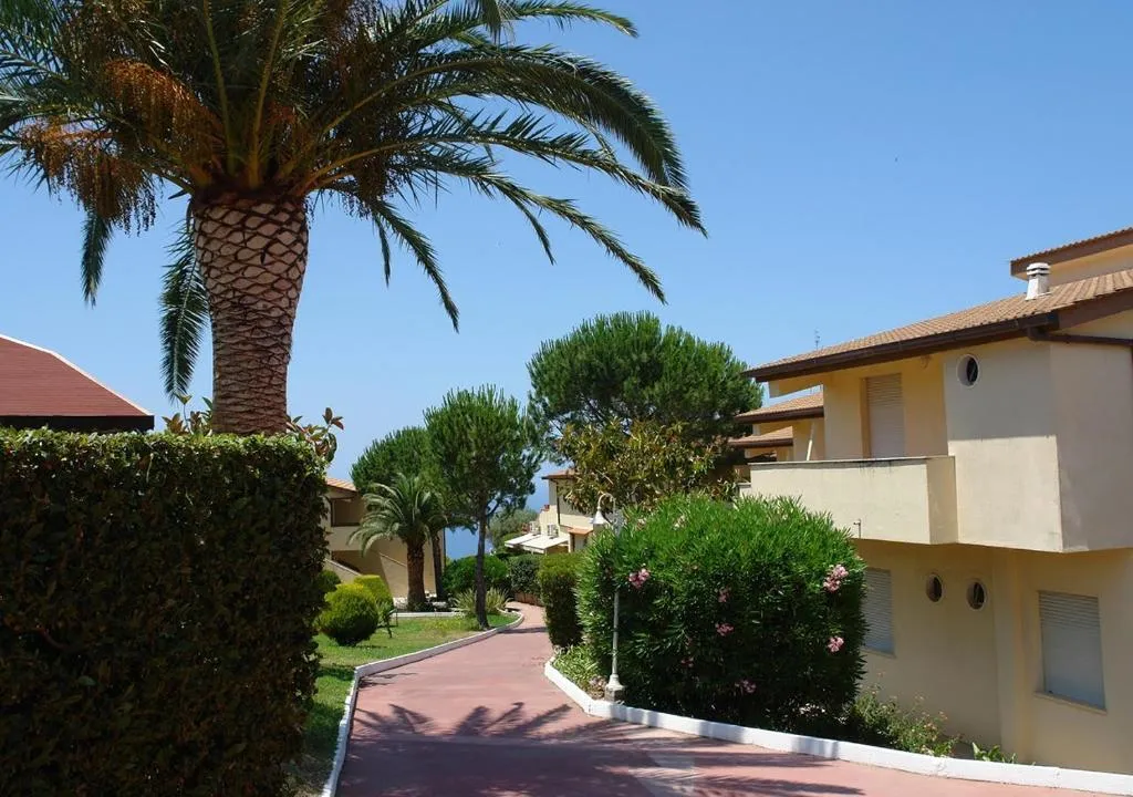 Vialetto del resort tra palme, siepi e edifici dai colori chiari