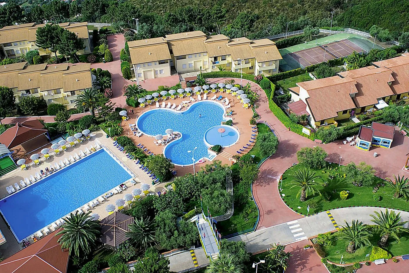 Vista aerea del resort con piscine, campo da tennis ed edifici tra il verde
