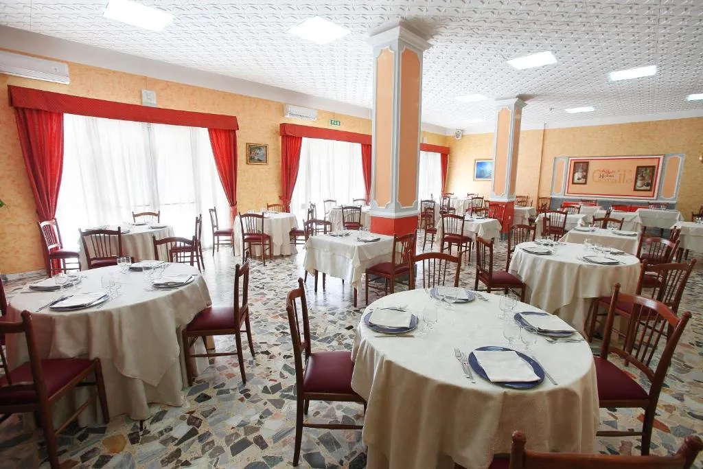 Sala ristorante con tavoli rotondi apparecchiati e pavimento in graniglia